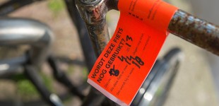 Op het stuur van een fiets zit een oranje label voor verwijdering