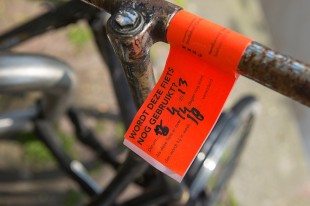 Op het stuur van een fiets zit een oranje label voor verwijdering