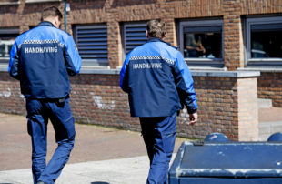 Afbeelding bij onderzoek Handhaving en overlast. Twee handhavers lopen bij een gebouw