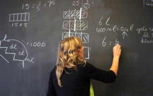 Afbeelding bij onderzoek Effectiviteit investeringen onderwijs. Een vrouw schrijft op een schoolbord